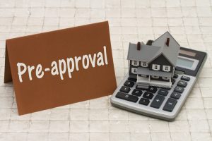 Sign saying, "Pre-Approved" next to a model home and calculator